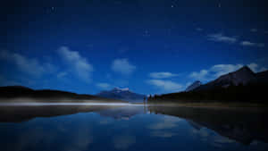 Céu noturno estrelado refletido em um lago de montanha calmo com margens enevoadas. — Evening Papéis de Parede