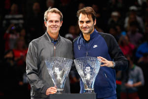 Due tennisti maschi che tengono trofei a una cerimonia di premiazione. — Federer Sfondi