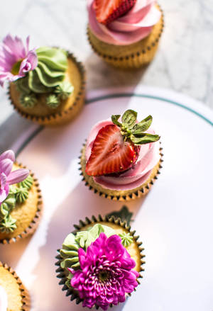 Cupcake colorati decorati con fragole e fiori su un piatto bianco. — Cupcake Sfondi