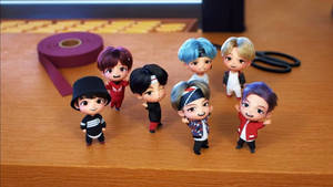 Chibi BTS figurines arranged on a wooden desk with craft supplies. — Tiny Tan Bts Wallpaper