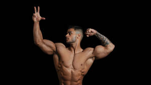 A muscular man with tattoos flexing his arms and making a peace sign. — Warrior Wallpaper
