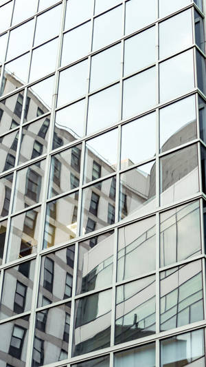 Close-up de um edifício de vidro refletindo outras estruturas urbanas e o céu. — Edifício Papéis de Parede