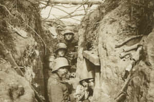 Soldiers in helmets crouch in a muddy trench during wartime. — War Wallpaper
