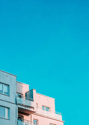 Moderne lejlighedsbygning med pastelrosa og grå facader under en levende cyan himmel. — Blå Wallpapers