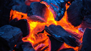 Braci ardenti e legno carbonizzato che irradiano calore nell'oscurità. — Calore Sfondi
