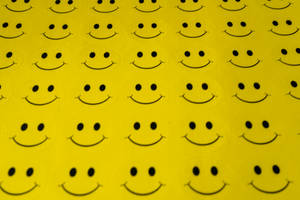 Wallpaper com rostos sorridentes pretos repetidos em fundo amarelo brilhante. — Amarelo Papéis de Parede