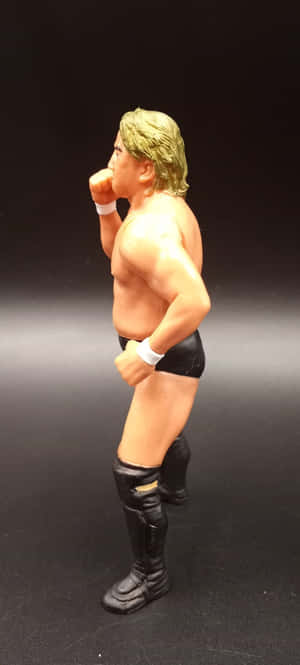 Wrestler action figure in fighting pose with blonde hair and black gear. — Pixel 9a Wallpaper