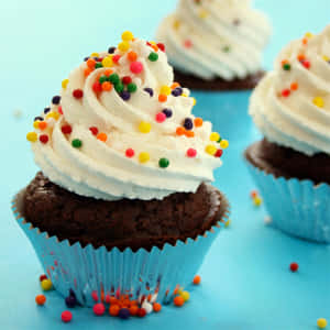 Cupcake al cioccolato con glassa bianca e codette colorate su sfondo blu. — Cupcake Sfondi