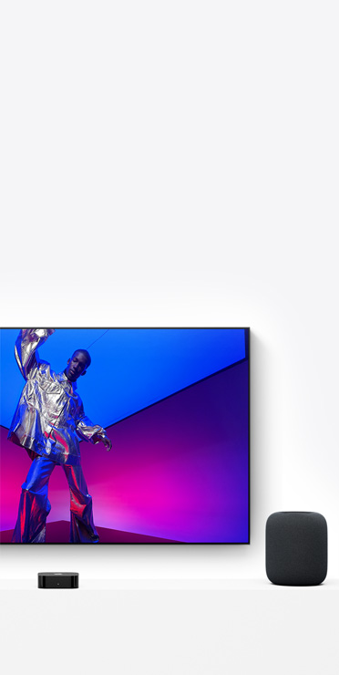 Apple TV 4K och HomePod i färgen midnatt, tv-skärmen visar en artist i metalliskt silverfärgad klädsel