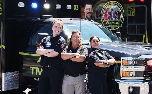 Three people stand in front of a truck.